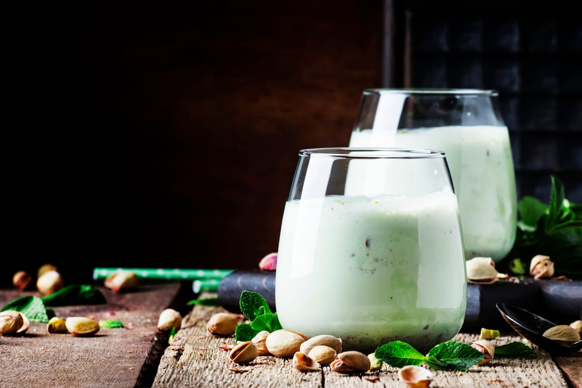 Deux verres de lait de pistache, couleur verte, avec des éclats de psitache autour