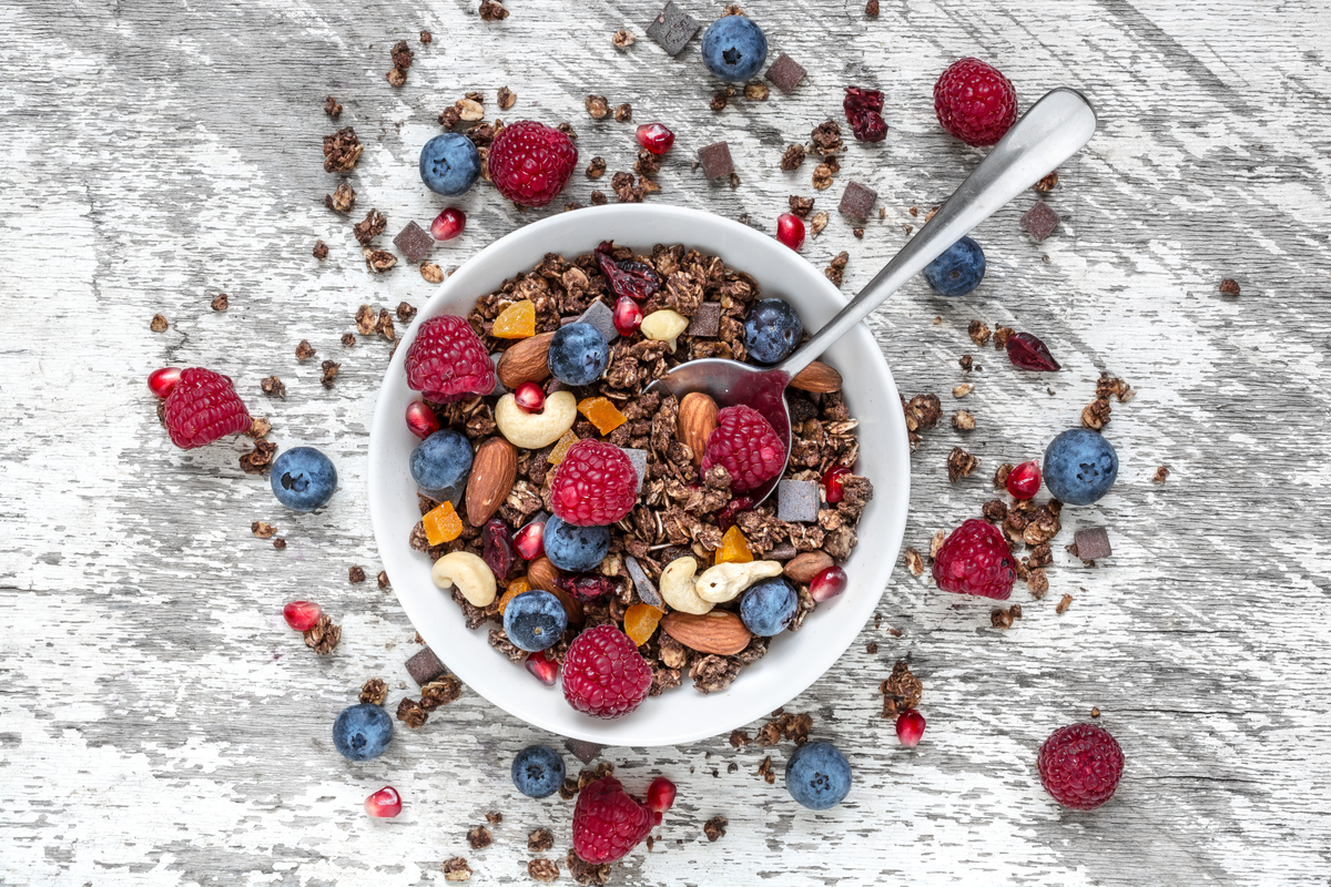 Granola dans un bol avec framboises, myrtilles, amandes, noix de cajou